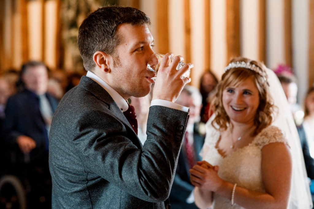 groom grabbing a glass of water during wedding
