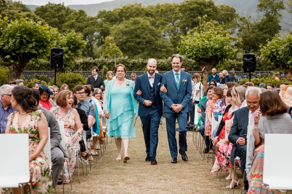 groom walking down aisle with parents