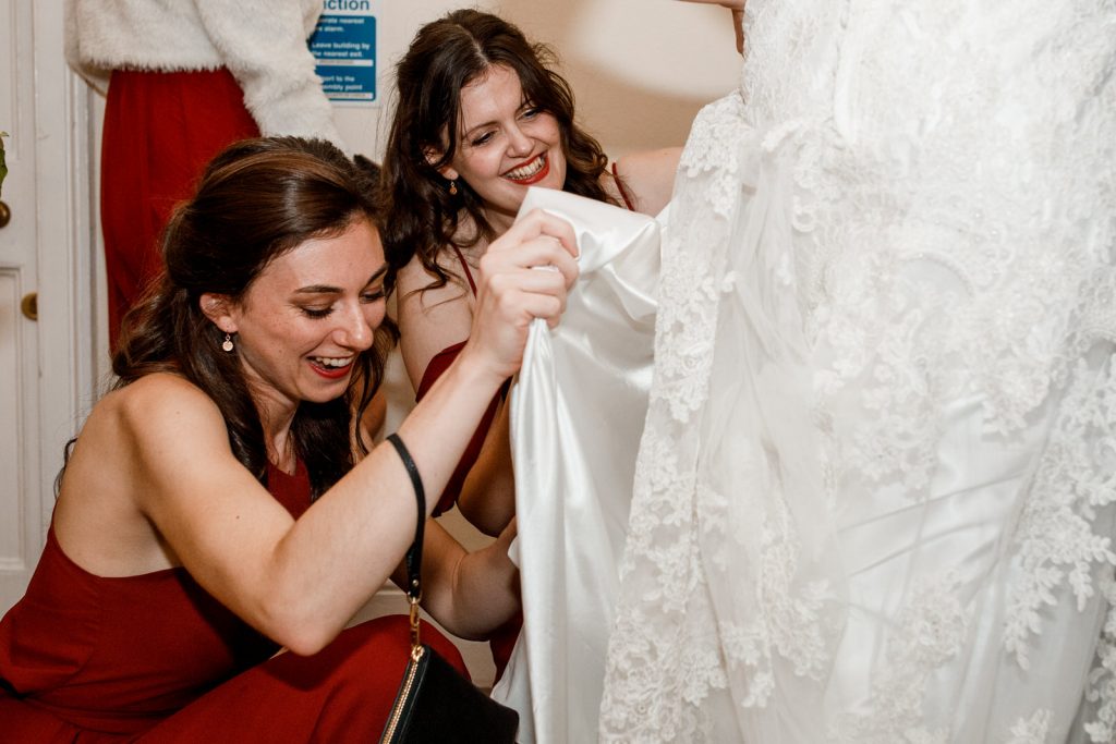 bridesmaid looking up brides dress and laughing