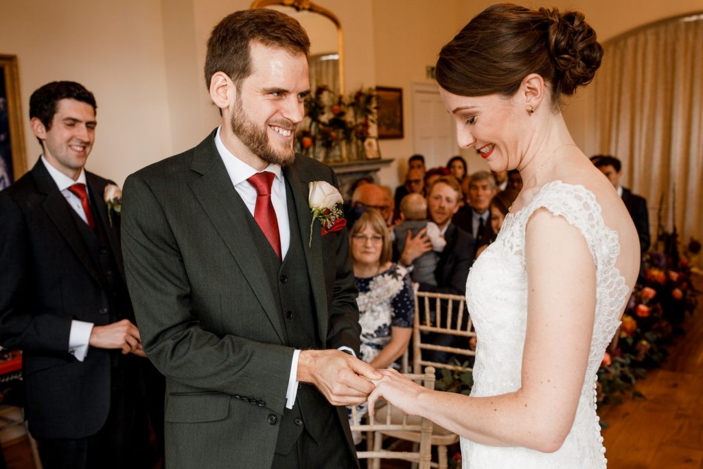 groom placing ring on brides finger at pembroke lodge wedding day