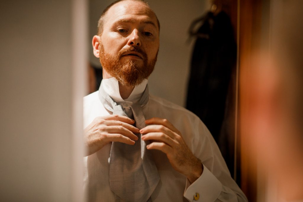 groom getting ready in mirror