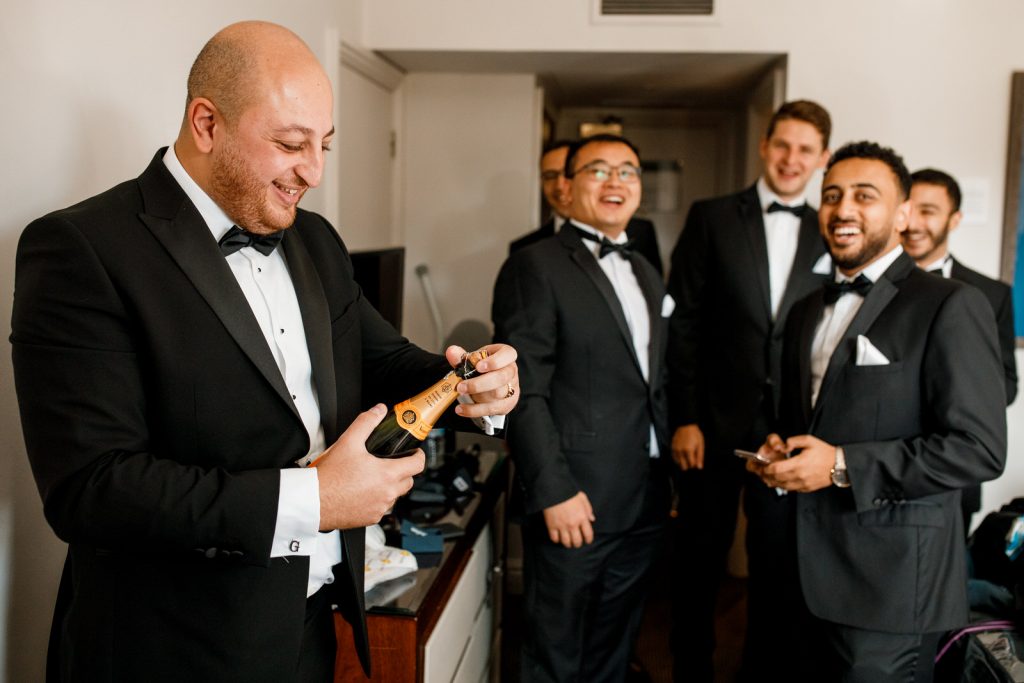 groom opening champagne with ushers