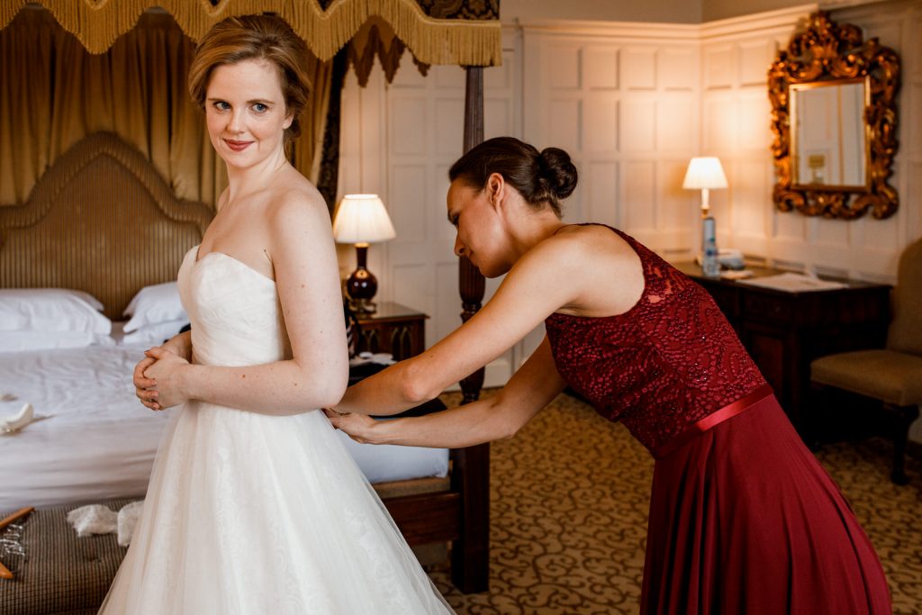 bridesmaid helping bride into her dress