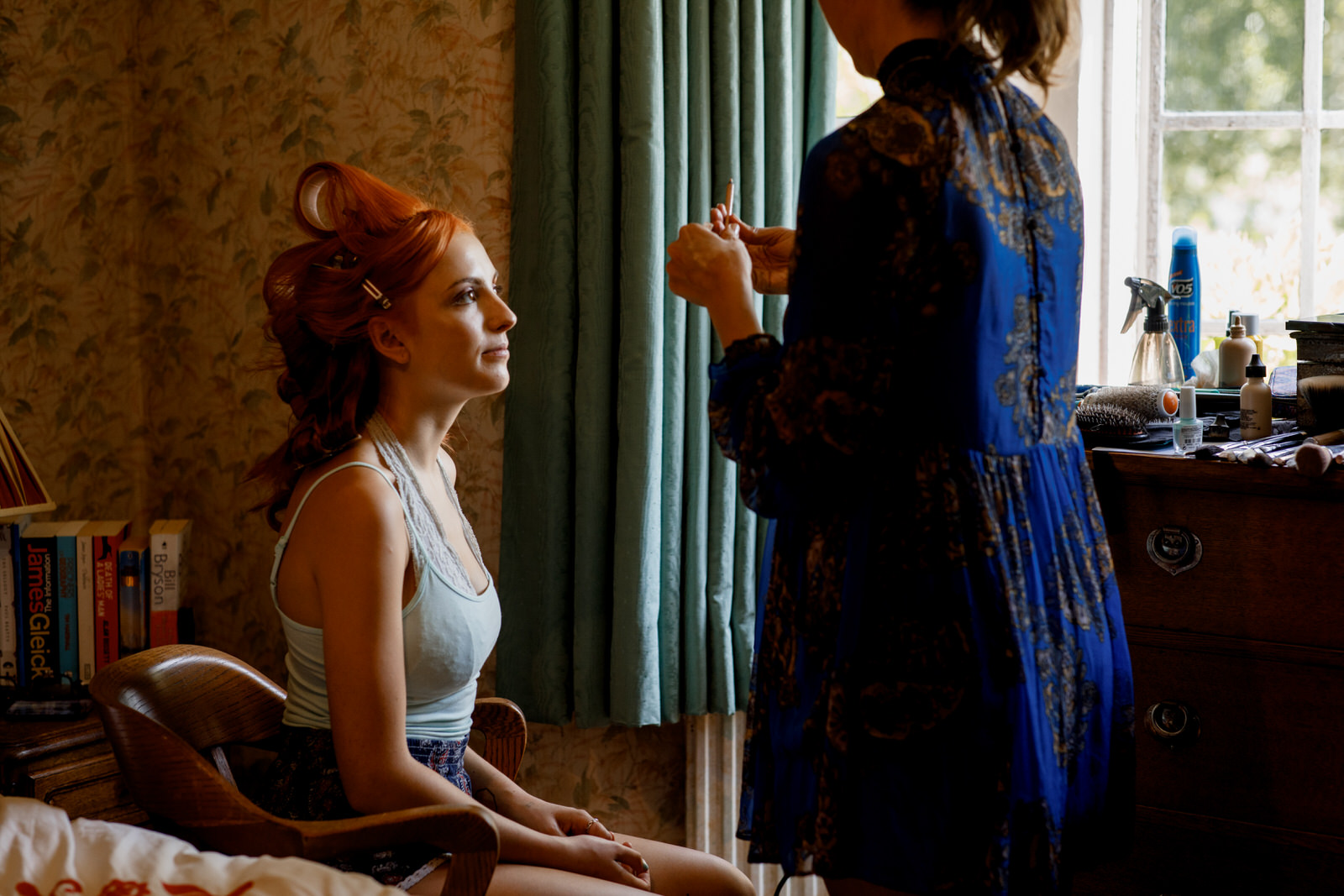 bride having make up applied in window light