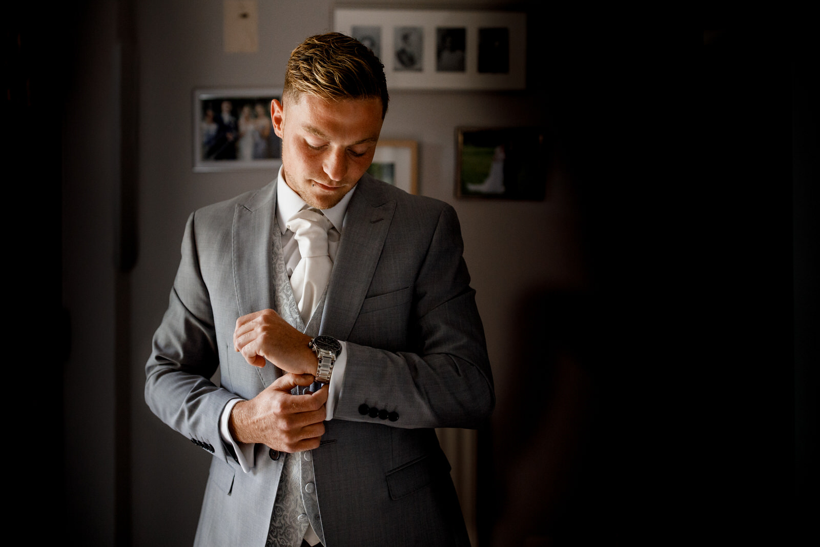 groom getting ready in window light