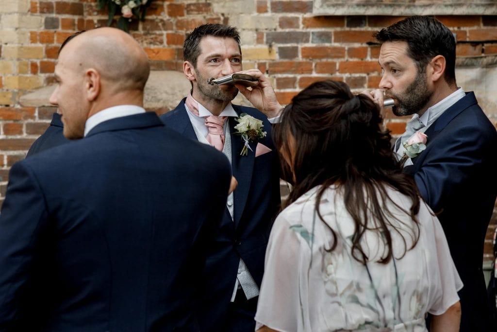 groom taking a drink from hip flask