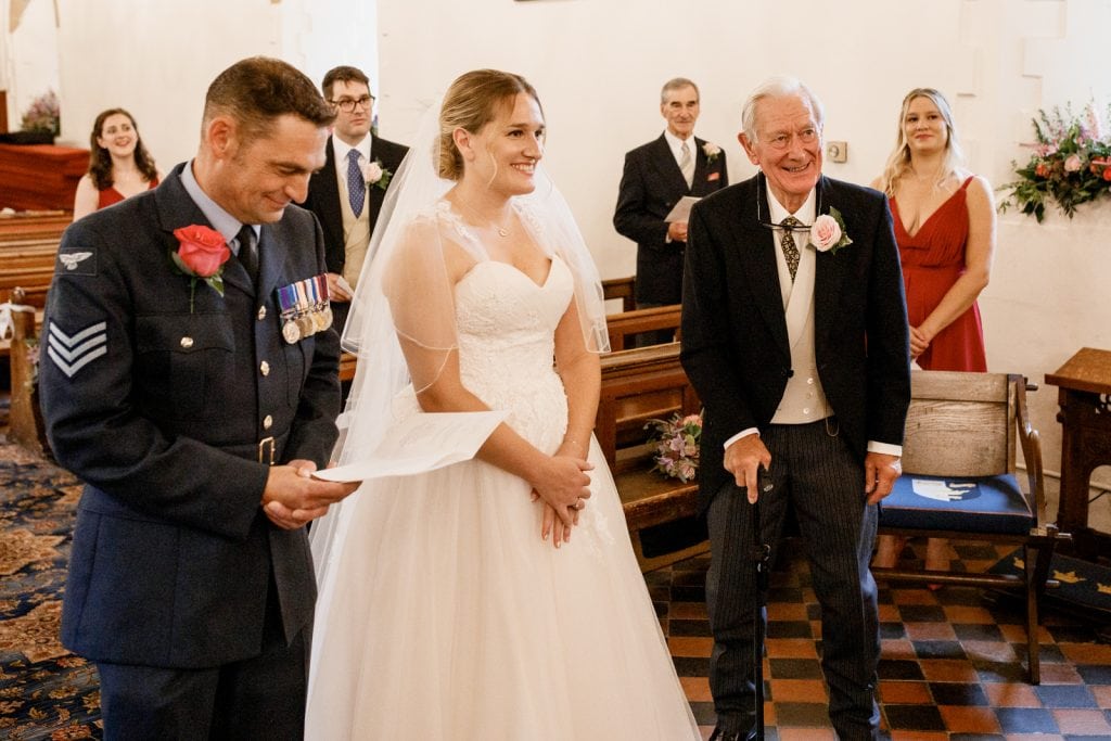 bride and groom at altar in church with father looking on
