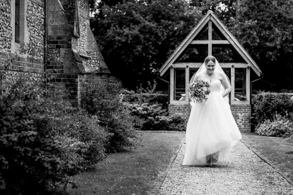 bride walking towards all saints church in coleshill for her wedding