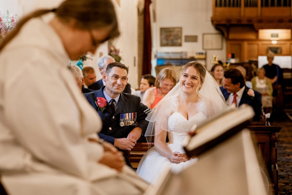 vicar praying with bride and groom in background