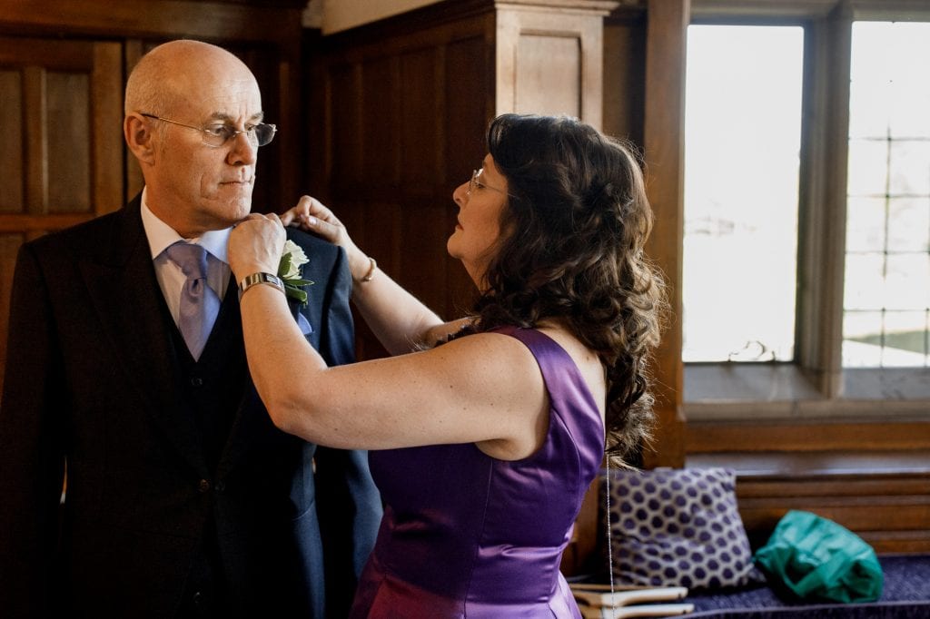 mother of bride arranging father of the bride suit